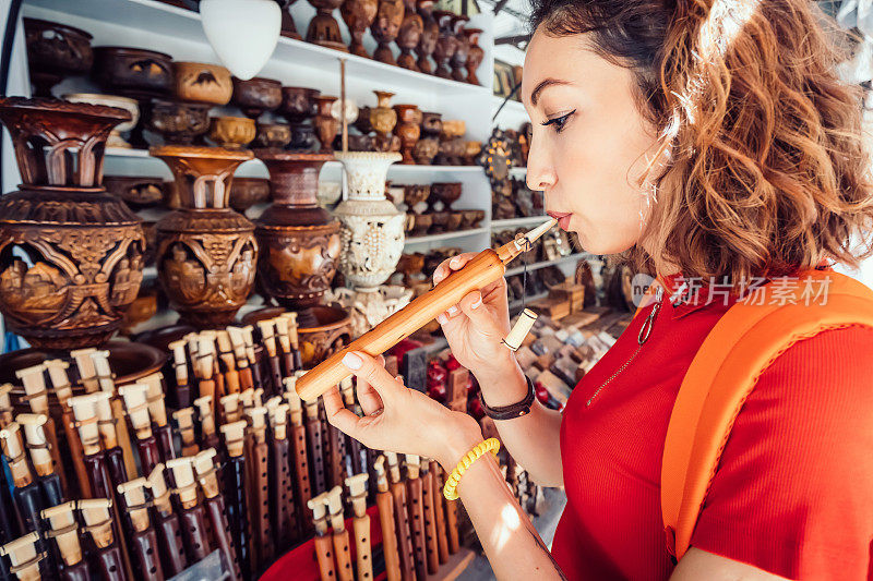 在埃里温的手工市场，一名女游客试图吹一种传统的亚美尼亚木制乐器duduk