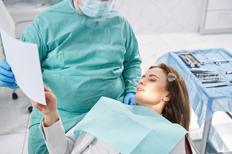 医生在口腔诊所向一位女士展示牙科扫描图