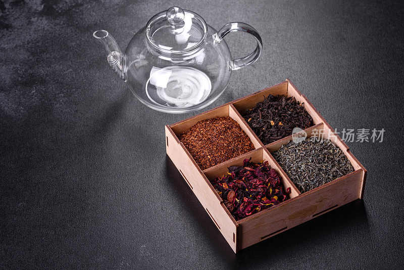几种干红茶与佛手柑，rooibos，绿色和框架在一个黑色混凝土背景的木制盒子