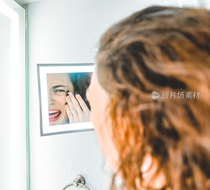 一个家庭浴室里的女人皱着眉头看着梳妆镜，也许是对自己的外表不满意