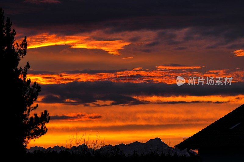 2021年圣诞节前夕。太阳升起时，村子上空有多云的红色天空。巴伐利亚,德国。