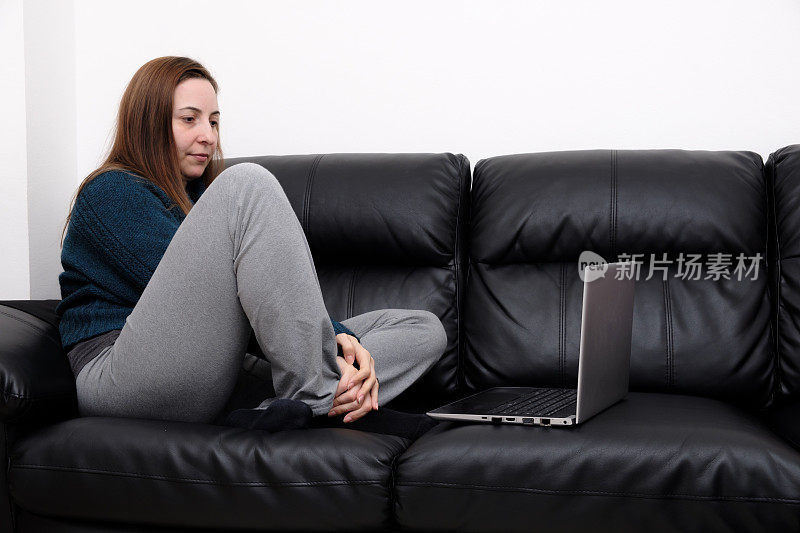 女人坐在沙发上用笔记本电脑看电影