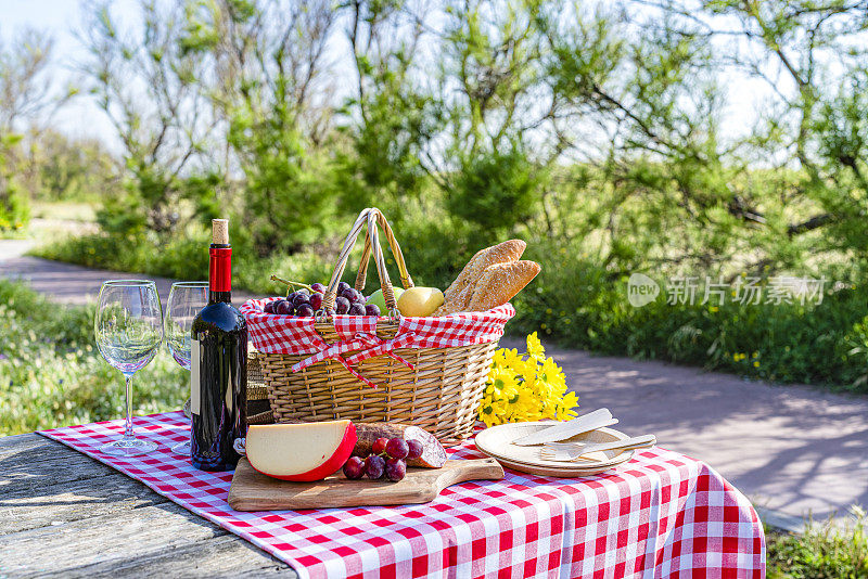 野餐篮和食物和酒放在户外的木桌上