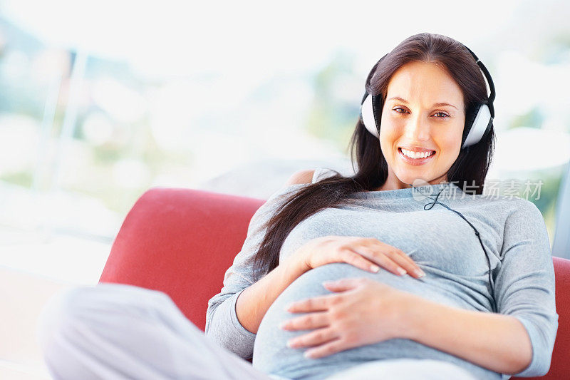 孕妇一边抱着肚子一边欣赏音乐