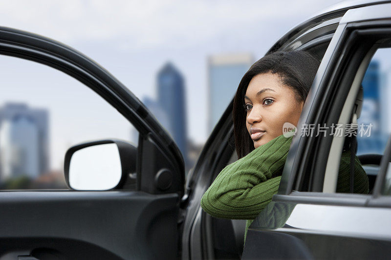 非裔美国少女坐在停着的车的驾驶座上
