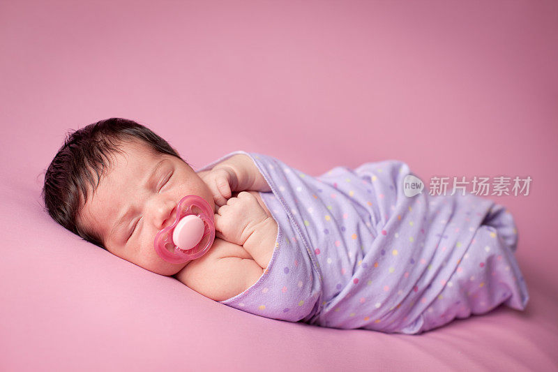 熟睡中的新生女婴裹着圆点毯子