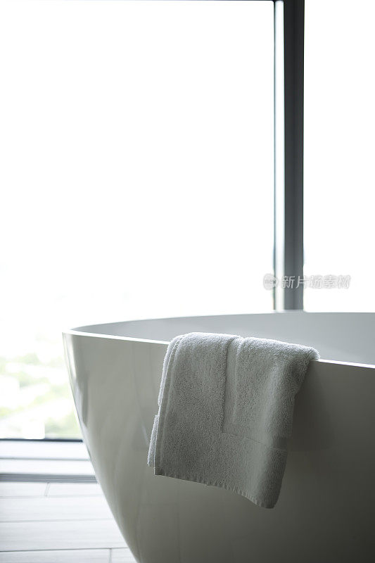 现代浴室，一个独立的白色浴缸靠大窗户