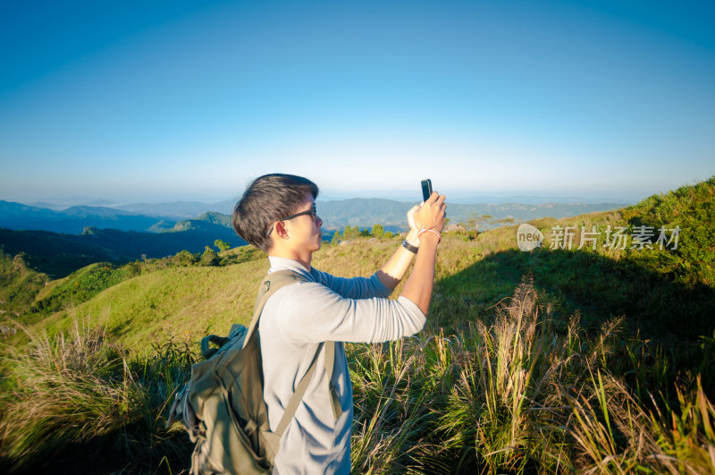 年轻的旅行者站在山上望着夕阳。