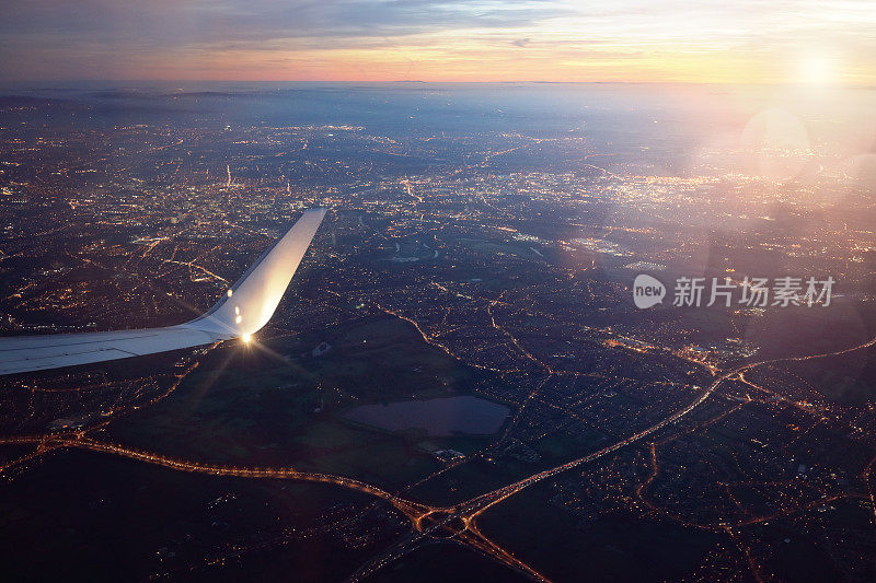 日落时从降落飞机窗口俯瞰城市