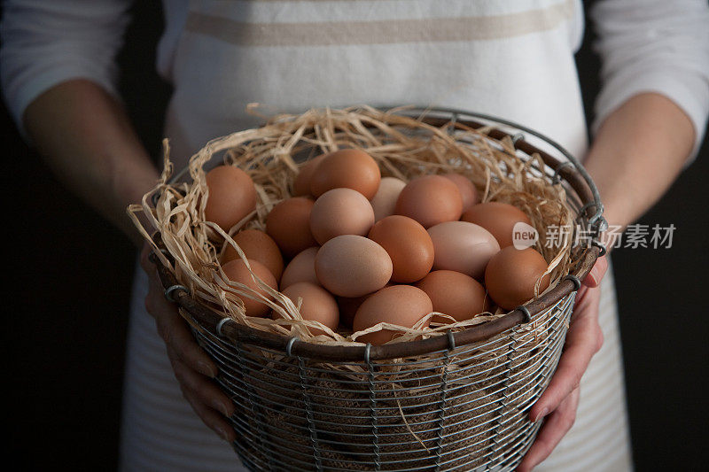 拿着一篮子新鲜农场鸡蛋的女人