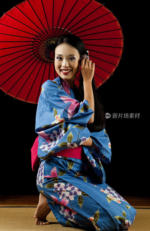 美丽的日本艺妓拿着一把红伞