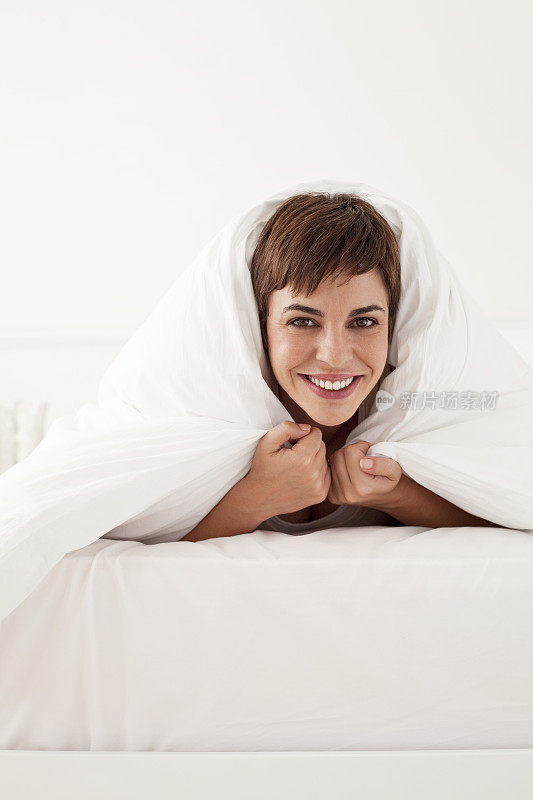 年轻女子在床罩下，头向外窥视