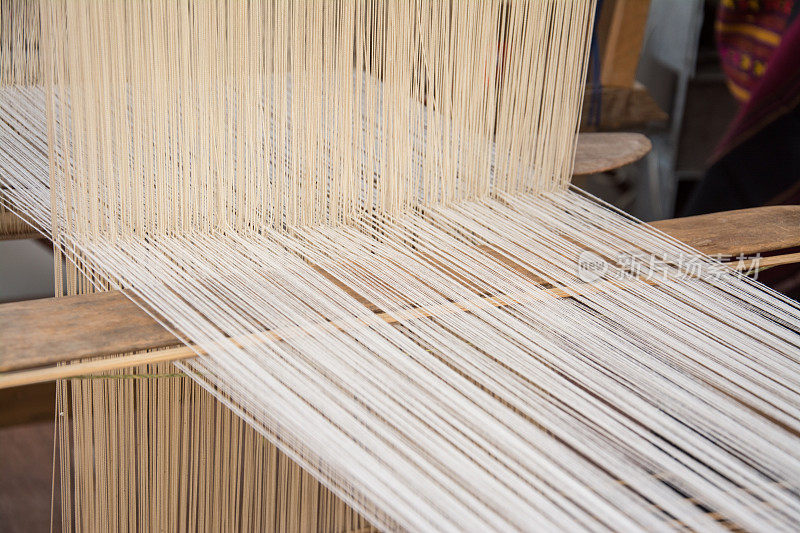 妇女在手工织布机上以传统方式织造丝绸。泰国