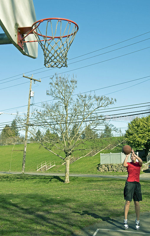 年轻女子在公园练习篮球时跳投