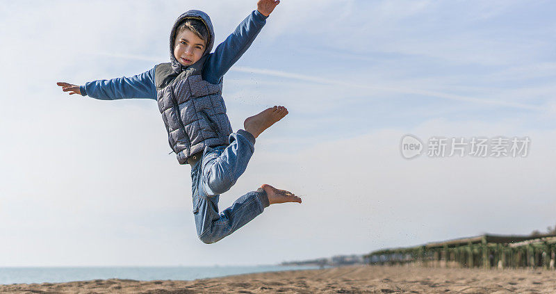 男孩在海滩上跳跃的肖像