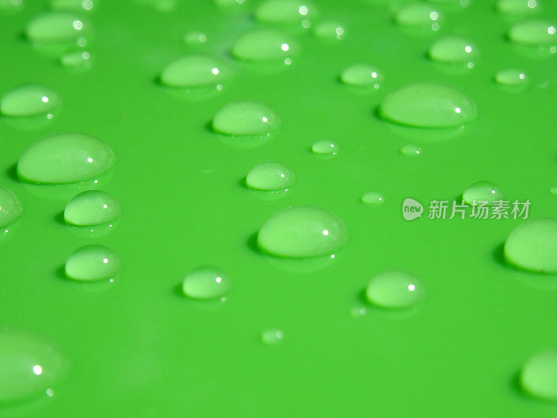 绿色塑料背景和特写水滴的图像，不同大小