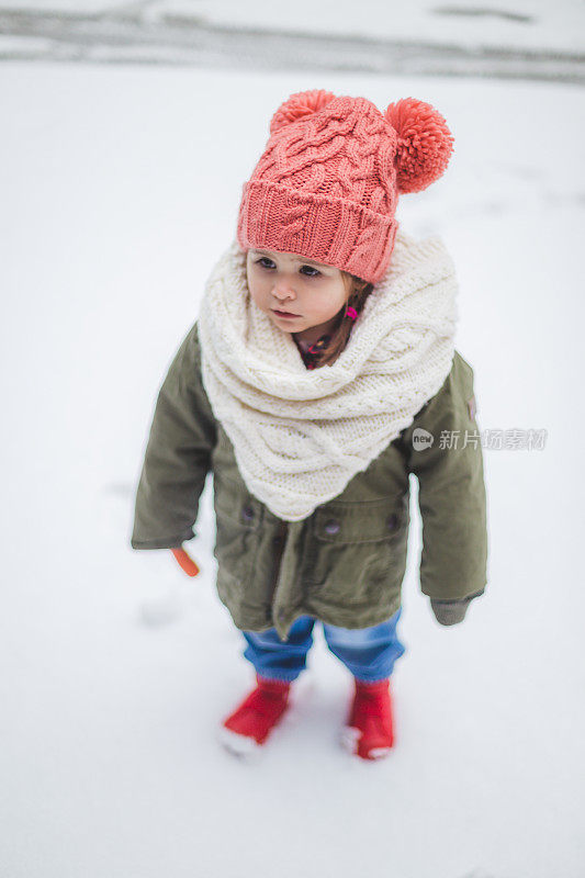 漂亮的小孩在冬天的衣服站在雪地上的肖像