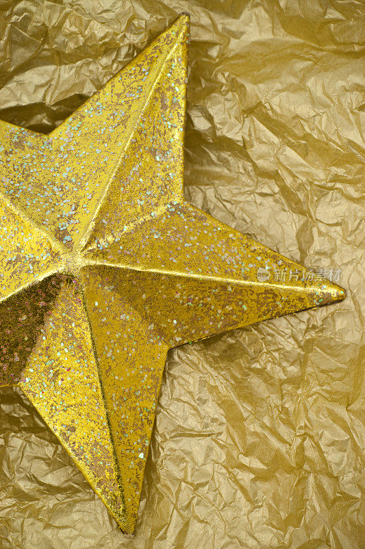 金色闪闪的圣诞星星装饰在金色的纸背景上