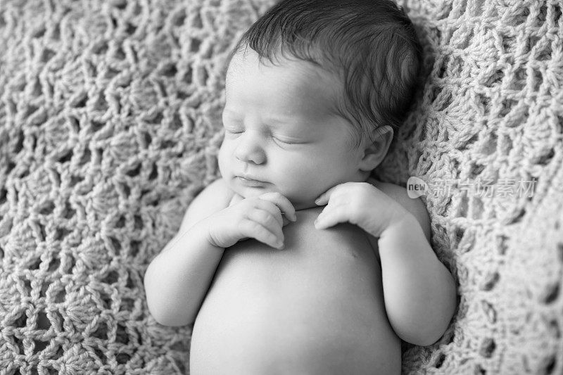 刚出生的婴儿安静地睡在针织毯子上
