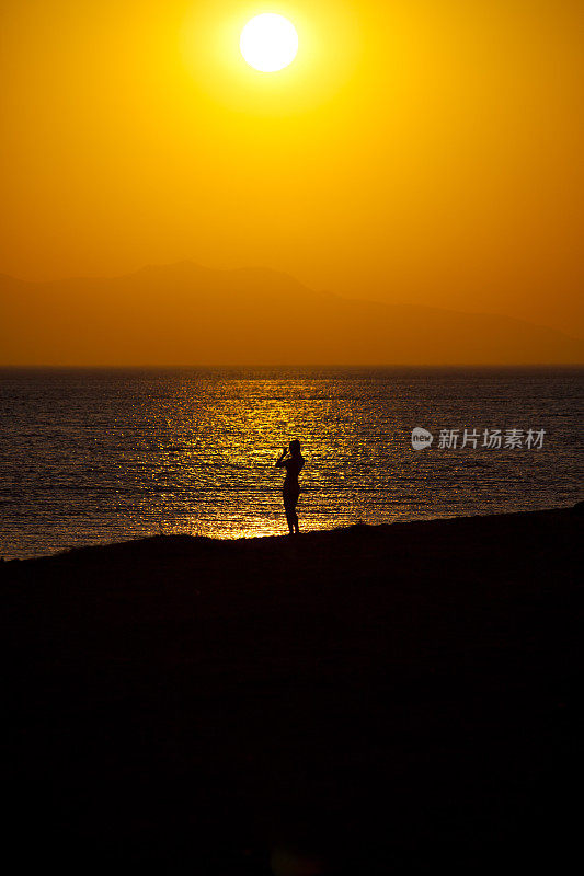 一位女士站在土耳其海滩上的夕阳下