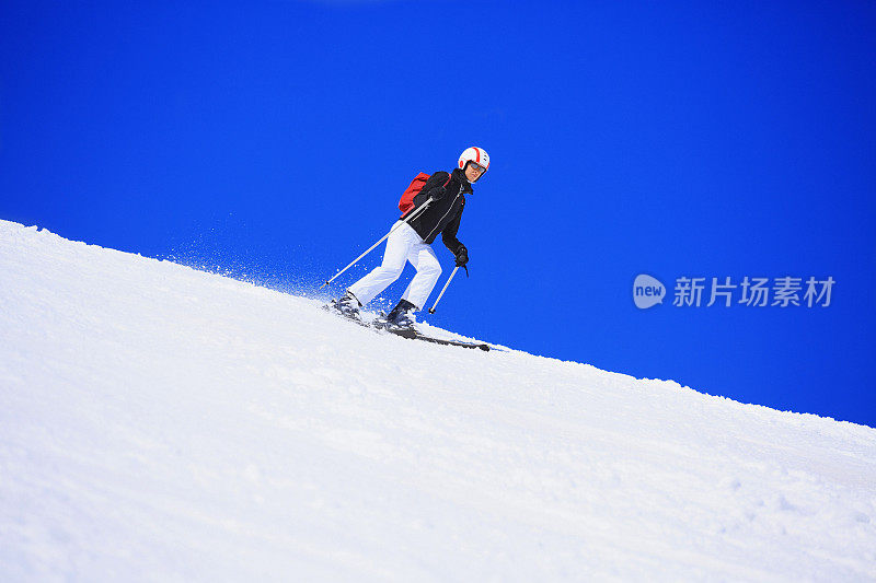 在阳光明媚的滑雪胜地滑雪的中年妇女滑雪