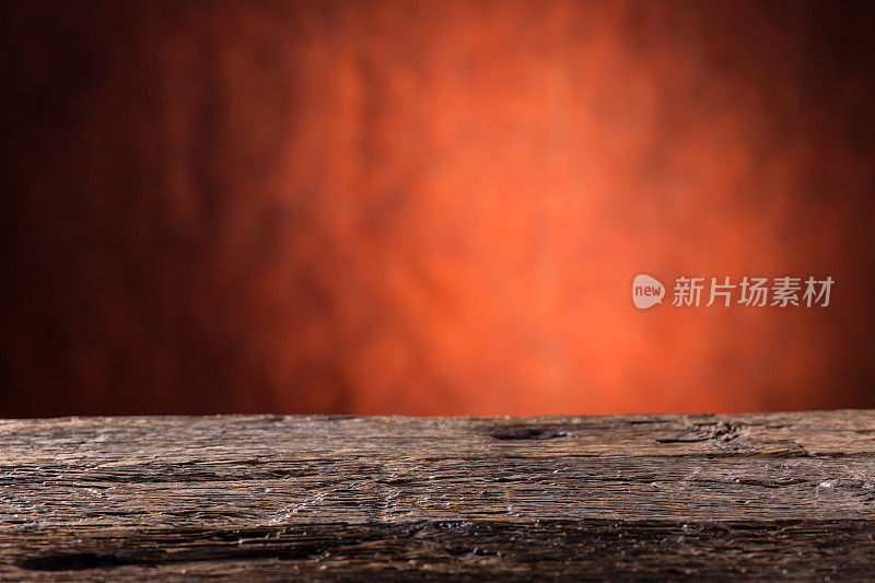 空橡木桌子和抽象的红橙色背景。为您的产品或信息提供免费空间