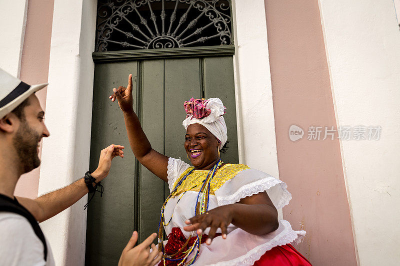 在巴西巴伊亚州萨尔瓦多的Pelourinho，游客与“Baiana”女子跳舞
