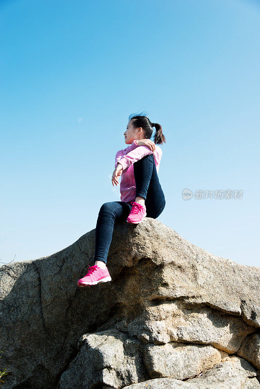 女人坐在山巅岩石的边缘
