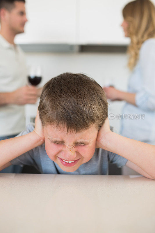 沮丧的男孩在父母争吵时捂住耳朵