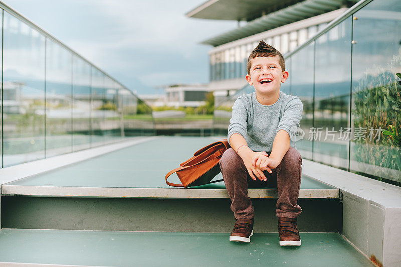户外写真快乐的小男孩。时尚男学生在外面休息。返校理念