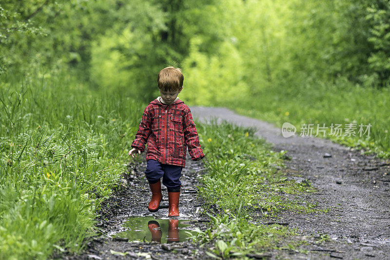 年轻可爱的孩子走着跳进水坑里