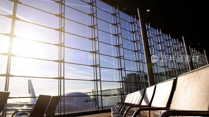 阳光明媚的机场候机楼里空荡荡的椅子，飞机站在窗户后面，开始登机
