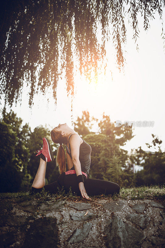 女性在夕阳下以劈开腿的姿势冥想