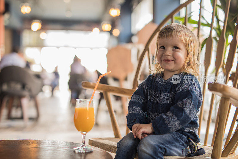 微笑的小男孩在咖啡馆的椅子上放松。
