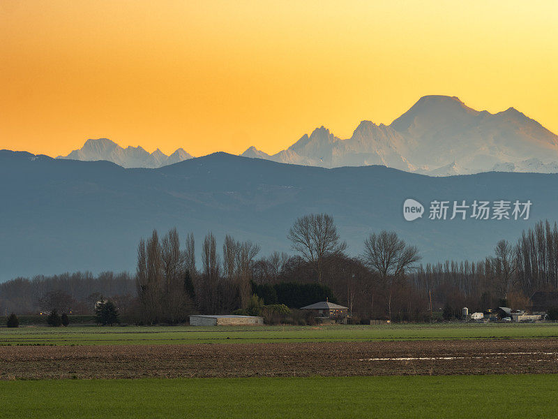 日落时分，风景如画的农田和雪山