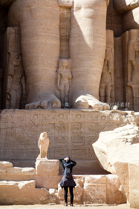 阿布辛贝-旅行者在埃及神庙外看着最左边的雕像在拉美西斯二世和奈费尔塔里神庙