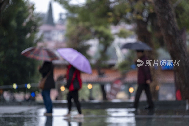 模糊的人们在雨中行走