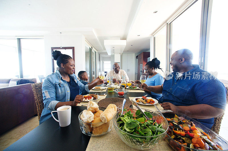 几代人的非洲家庭在午餐桌旁欢呼