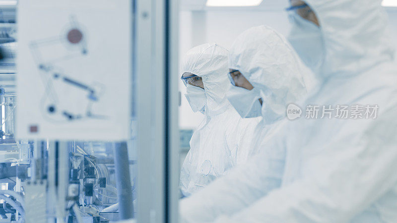 一组科学家穿着无菌防护服在现代工业3D打印机器上工作。制药、生物技术和半导体制造工艺。