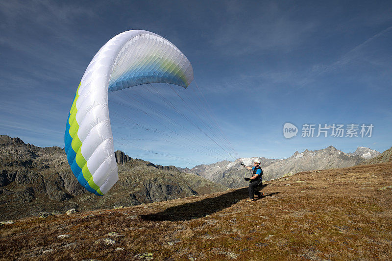 年轻的滑翔伞飞行员练习他的滑翔伞在风中拉起，这就是所谓的地面操作。在瑞士阿尔卑斯山的格里姆塞尔附近