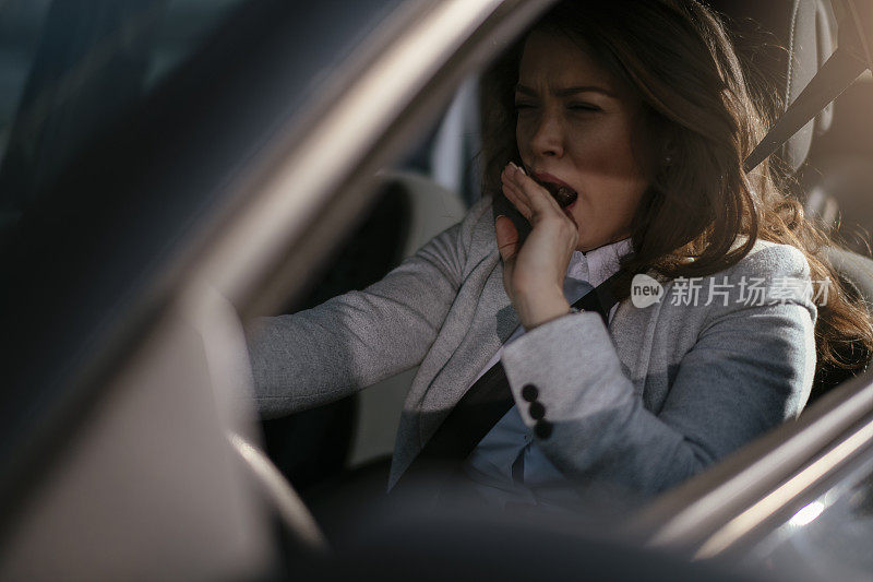 女商人开车累了昏昏欲睡的女商人开着她的车