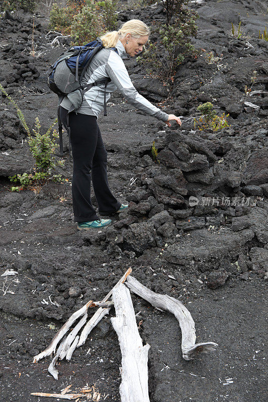 女性徒步旅行者沿着火山熔岩向前走