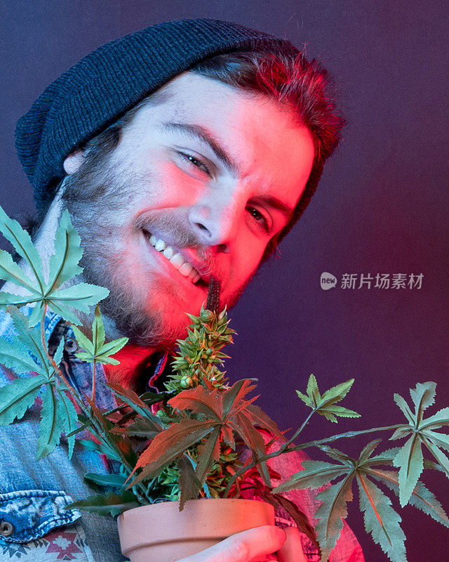 年轻的瘾君子和大麻植物站在一起