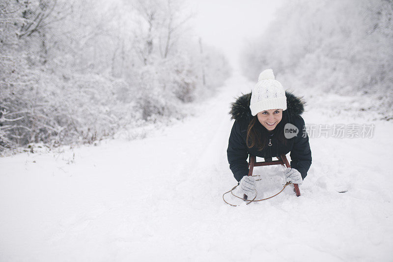 年轻女子在深雪中玩雪橇