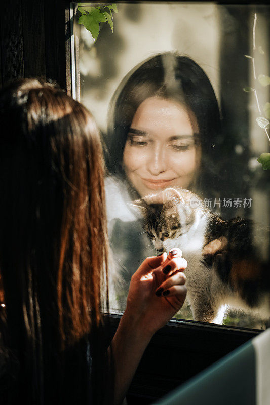 快乐的女人喜欢窗户后面的猫