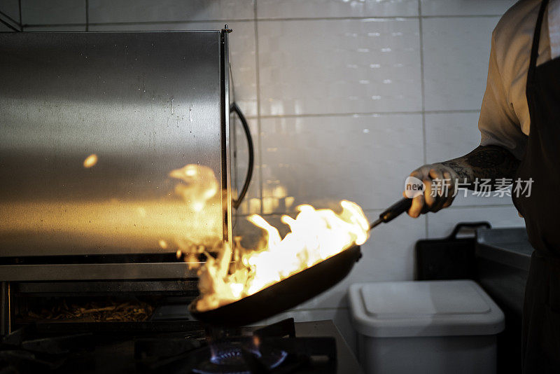 厨师在商业厨房用平底锅准备火焰粉