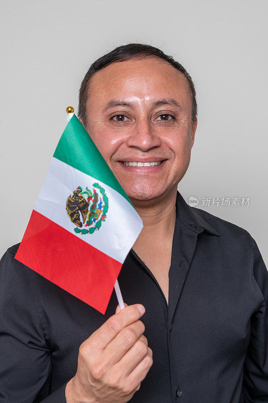 一个成熟的西班牙人举着一面小小的墨西哥国旗