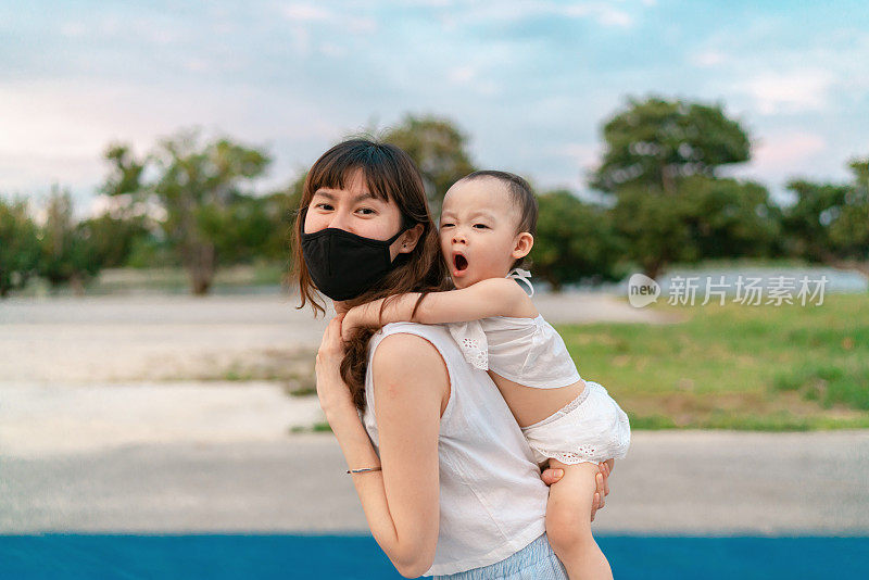 亚洲母亲照顾她的孩子，同时在户外探索冠状病毒大流行