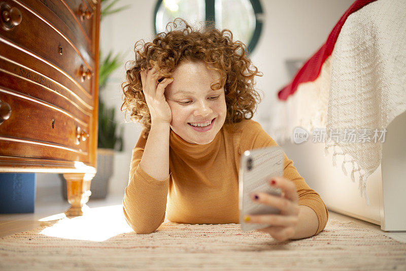 年轻的红发女人在家里用智能手机