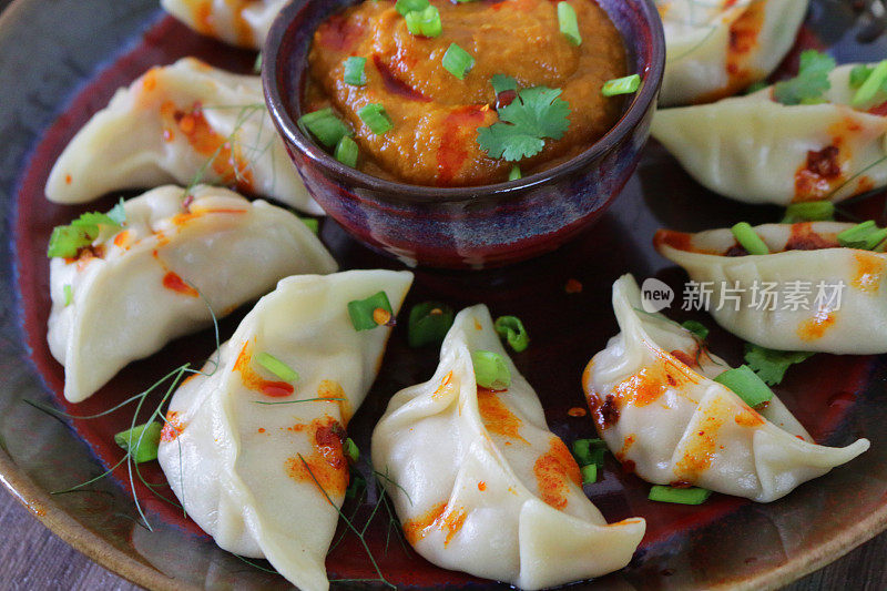 这是蒸过的馍馍(南亚饺子)，用白面粉和水面团填满鸡肉和什锦蔬菜，淋上辣椒油，放在盘子里，周围是用橙子辣酱做的小模子